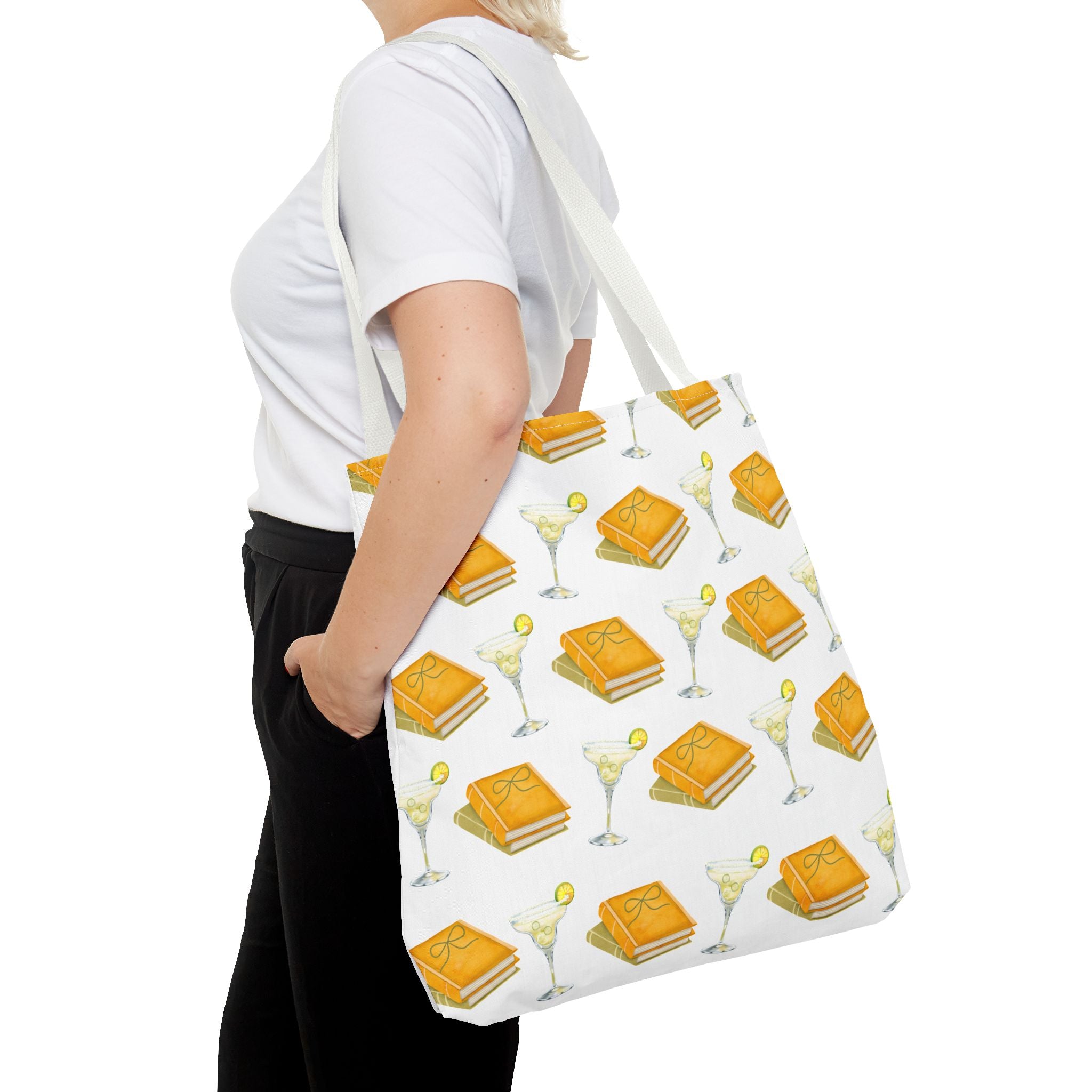 Person holding a tote bag with a pattern of books and drinks on a white background