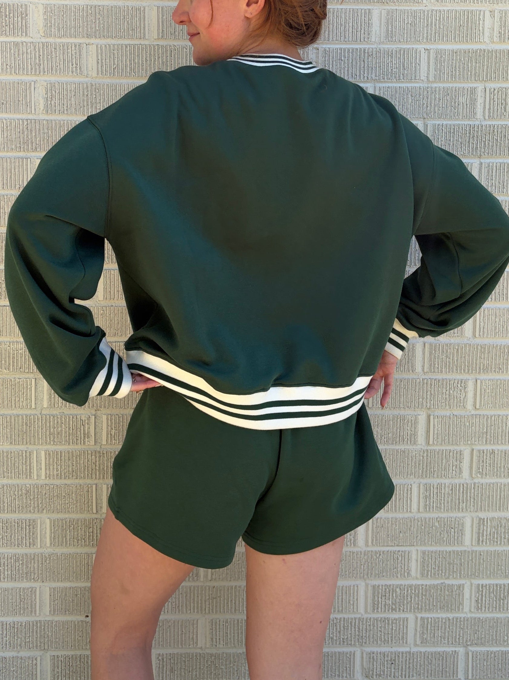 Person wearing a green tracksuit with white stripes on a tiled floor