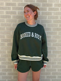 Person wearing a green sweatshirt with text on a tiled floor