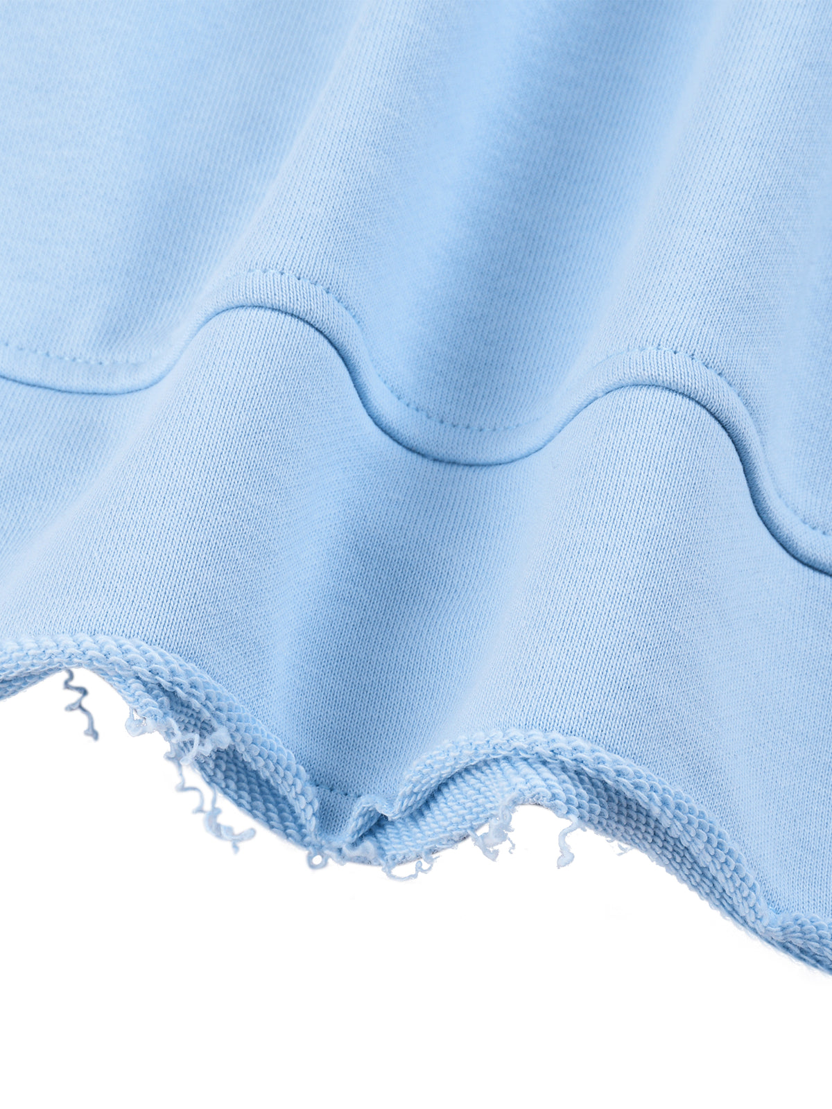 Close-up of a light blue fabric garment showing a wavy scalloped edge and frayed raw hem against a white background.