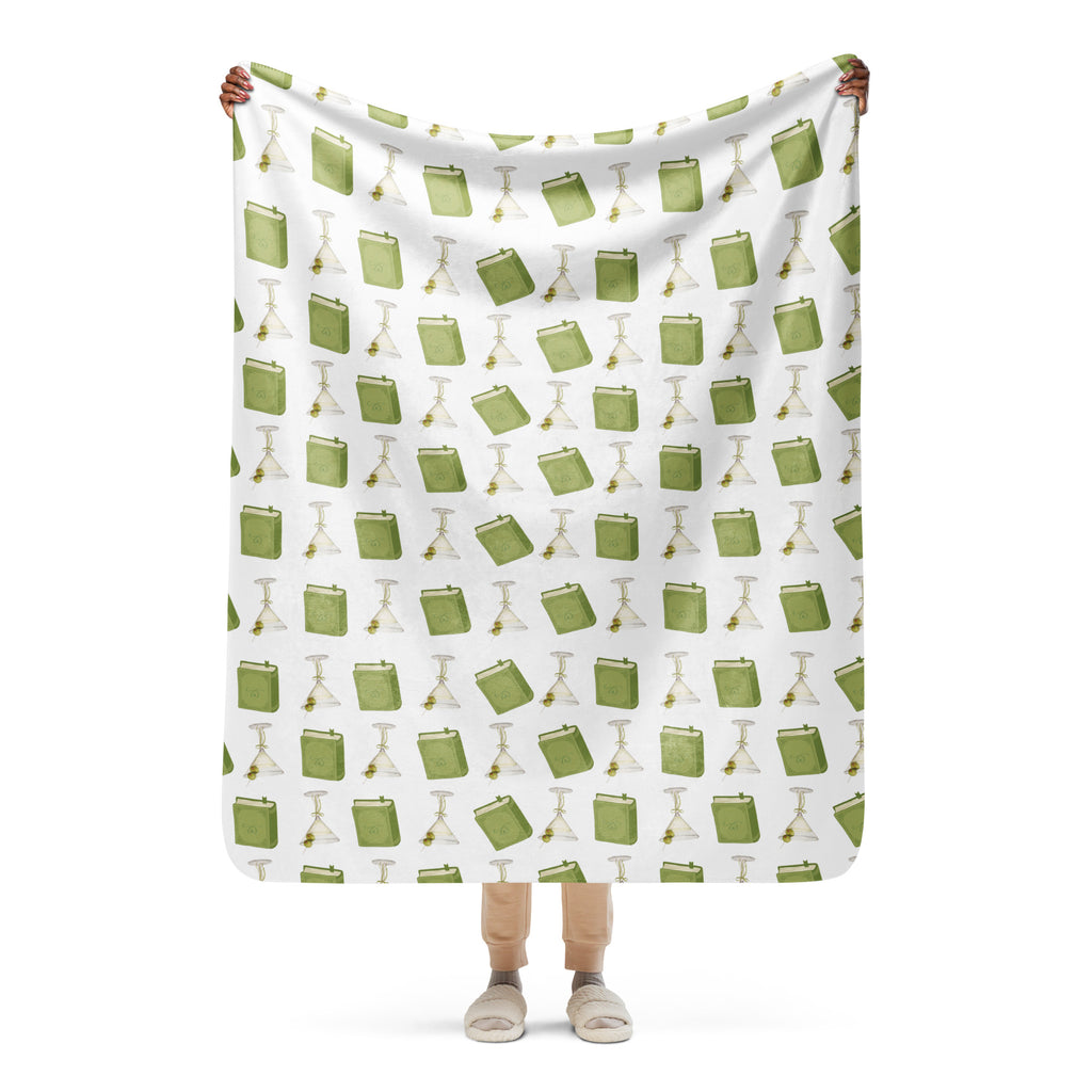 woman holding 50x60" sherpa lined blanket with dirty martinis and green books on it , product mock-up image