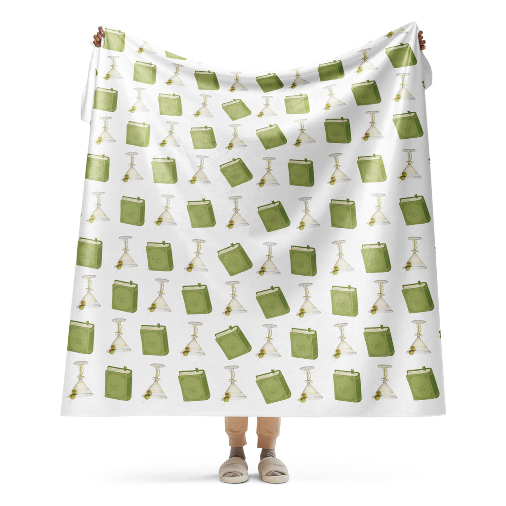woman holding 60x80 " sherpa lined blanket with dirty martinis and green books on it , product mock-up image