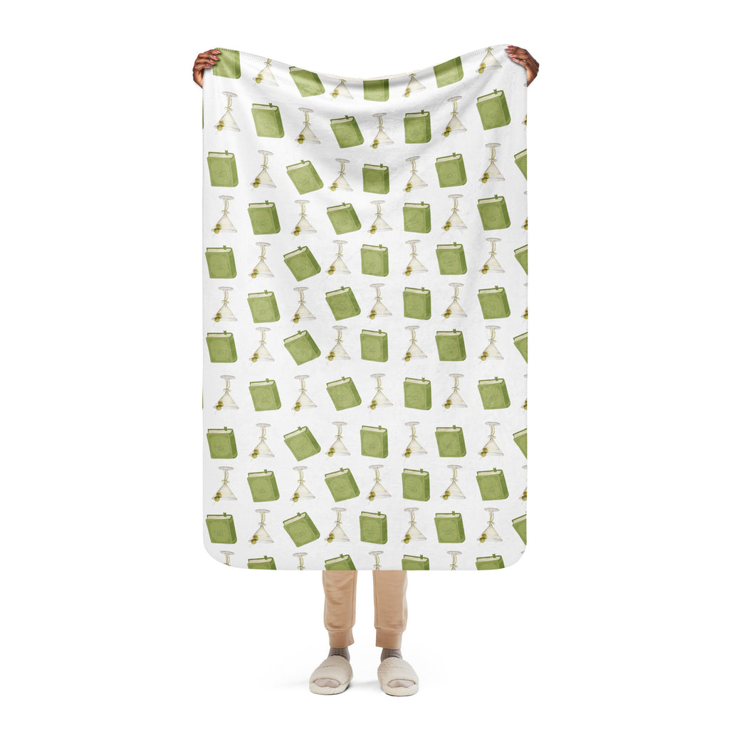 woman holding 37x50 " sherpa lined blanket with dirty martinis and green books on it , product mock-up image